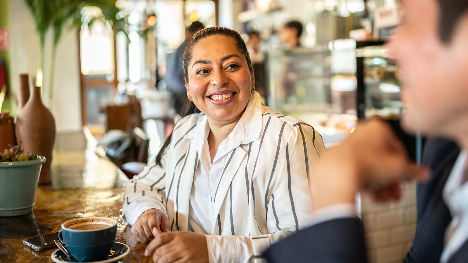 Businesswoman smiling at man in business suit while having coffee in a cafe