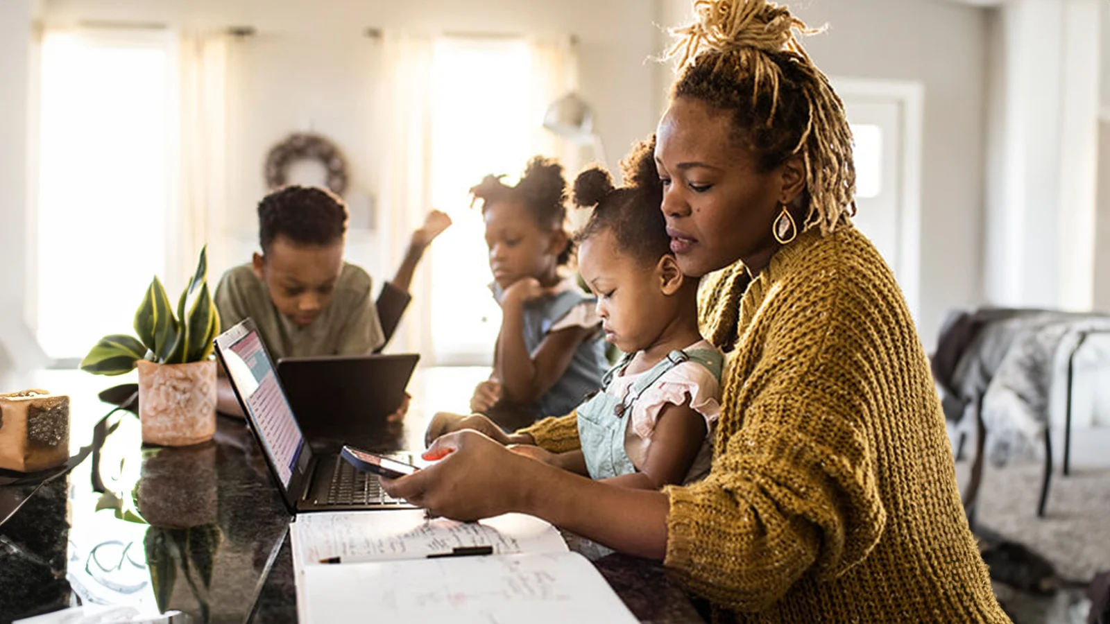 How employers can support caregivers with increased responsibilities - Mother texting on her phone while holding her daughter