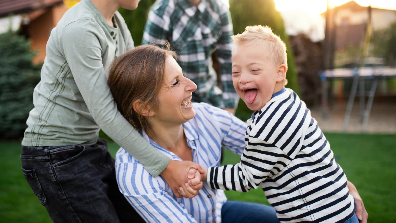 Mother and her son with down syndrome playing outside with family.