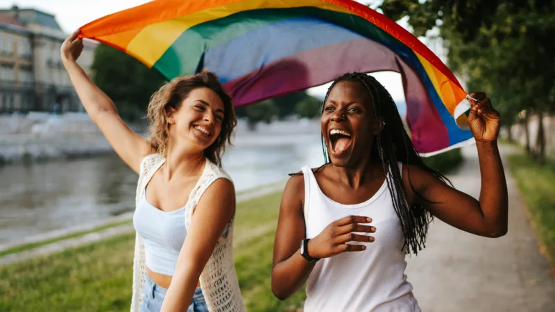 Recognition - Two females in LBGTQ community proudly waving pride flag