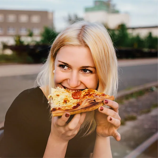 Woman eating pizza outside