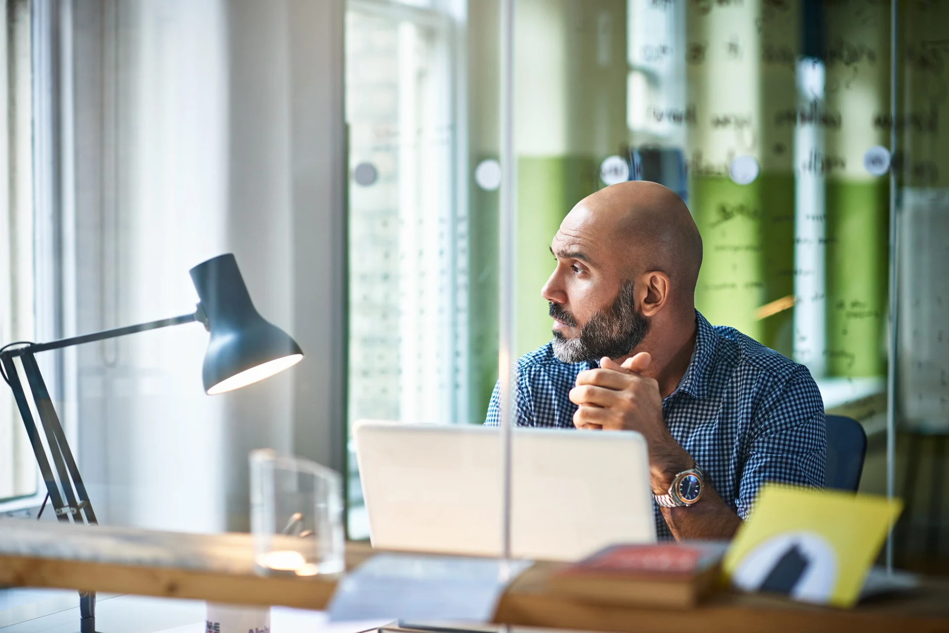 Man in front of a laptop looking out a window