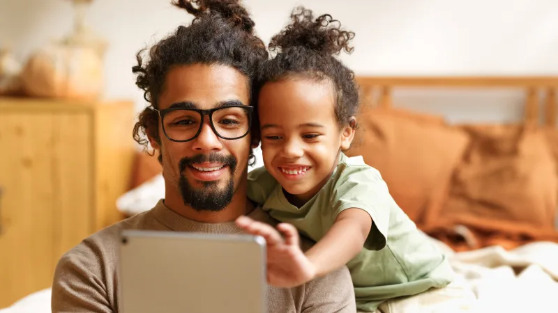 A dad and daughter gather around an iPad