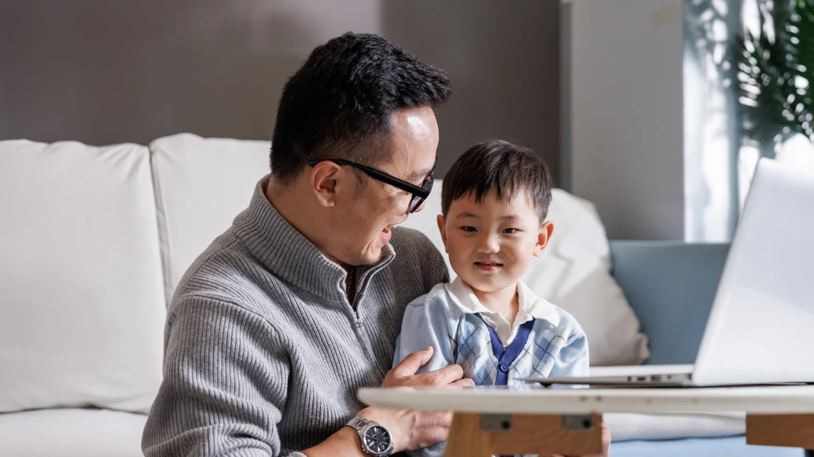 Father holding his son on his lap while working on his laptop