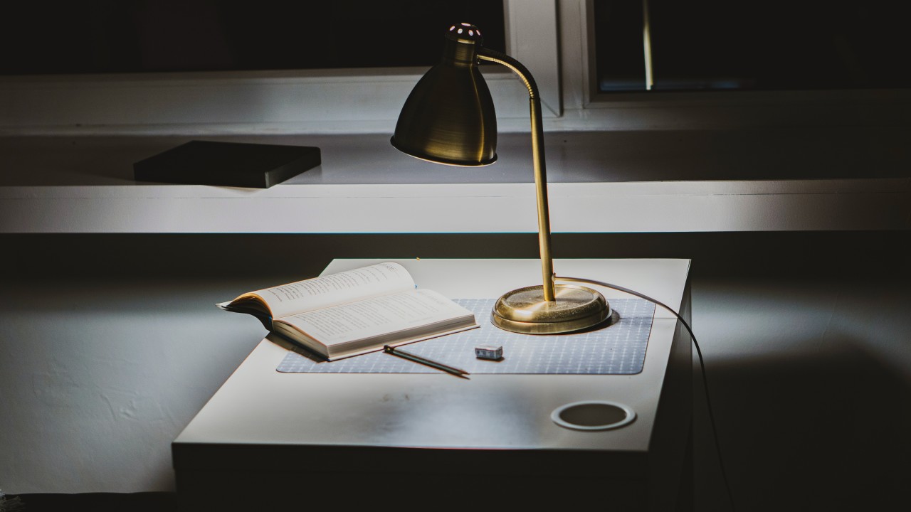 Goldene Schreibtischlampe beleuchtet ein Buch