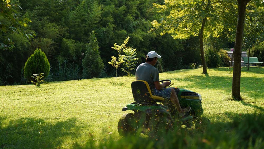 Ein Mann mäht den Rasen mit einem Rasentraktor