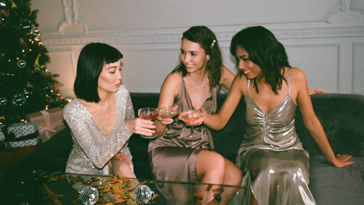 Drei Frauen in Cocktailkleidern stoßen an