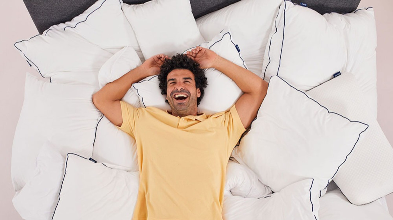 Ein Mann liegt auf einem Bett voll mit Kopfkissen