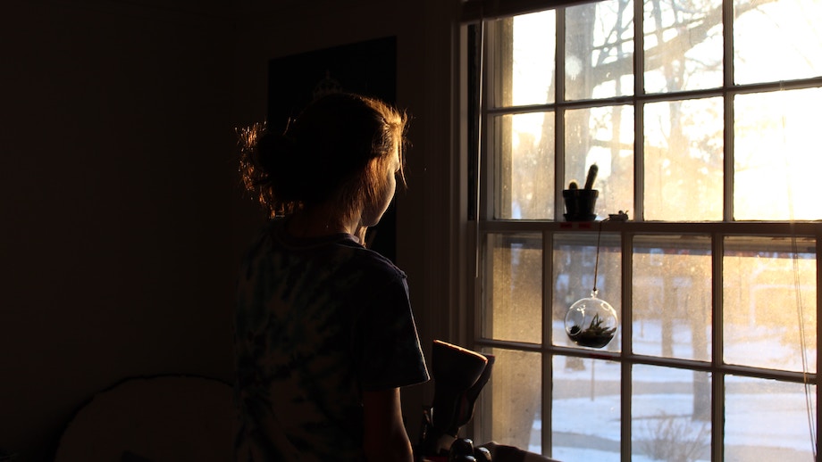 Eine Frau schaut aus einem Fenster auf eine schneebedeckte Landschaft