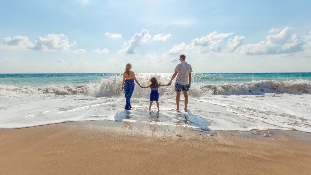 Eine Frau, ein Mann und ein Kind gehen am Strand spazieren