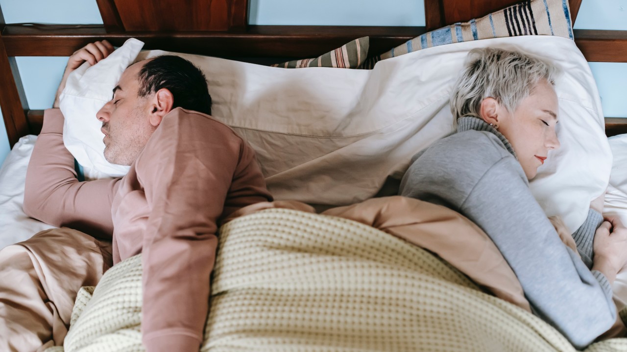 Mann und Frau schlafen nebeneinander auf der Seite