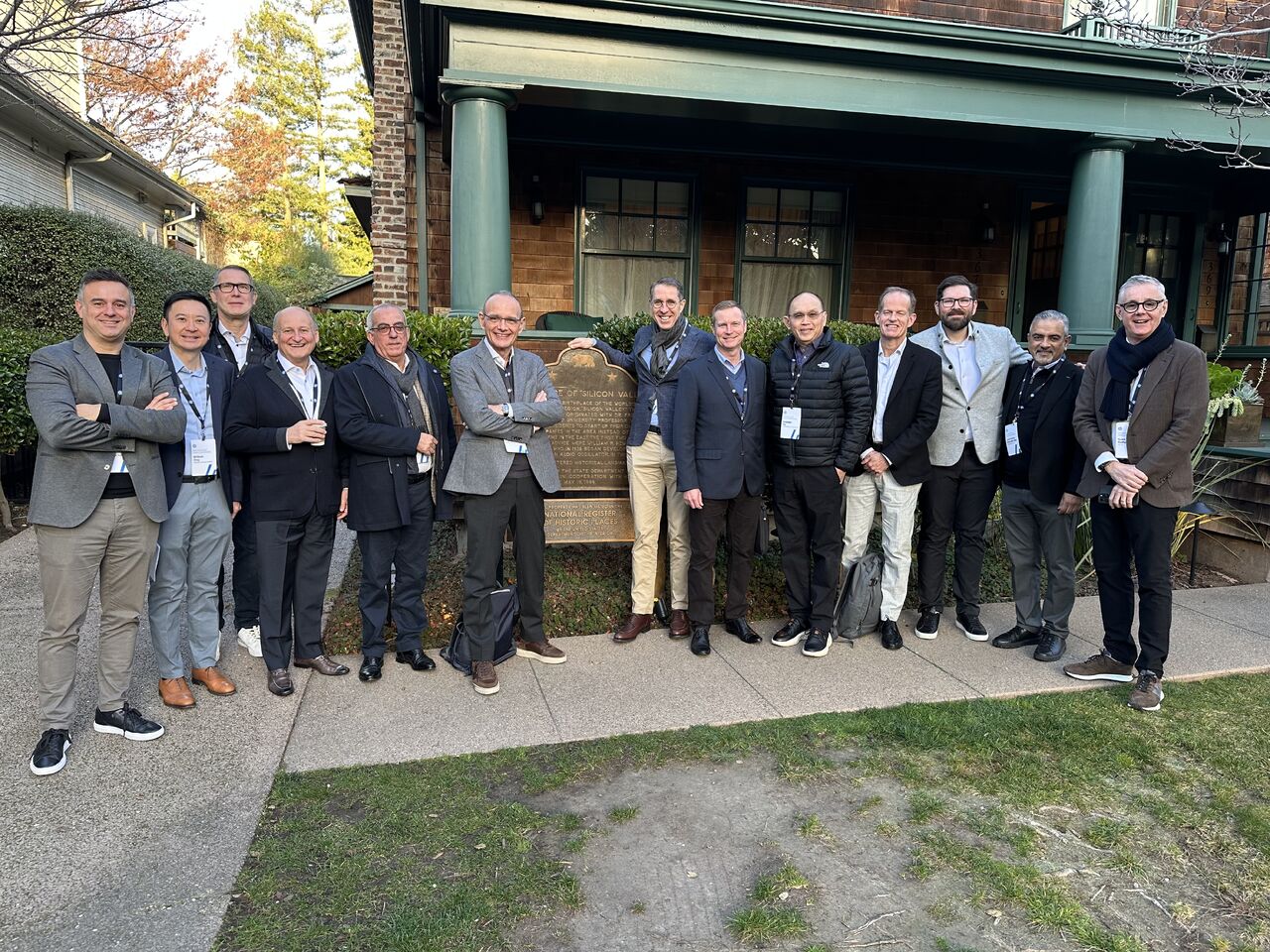 Company members on a business trip posing in front of a housing structure.
