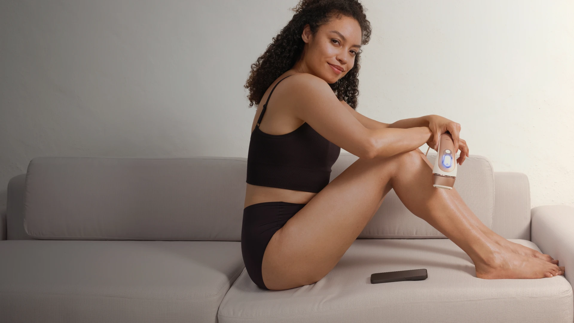 A woman sitting on a couch with product in her hand.