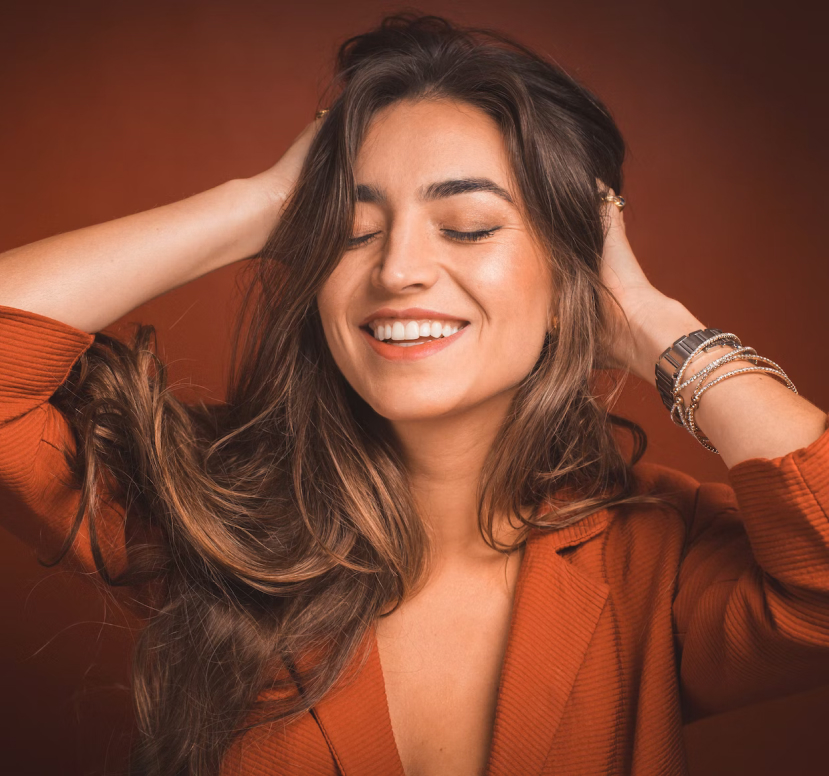 Girl holding hair with eyes closed smiling.