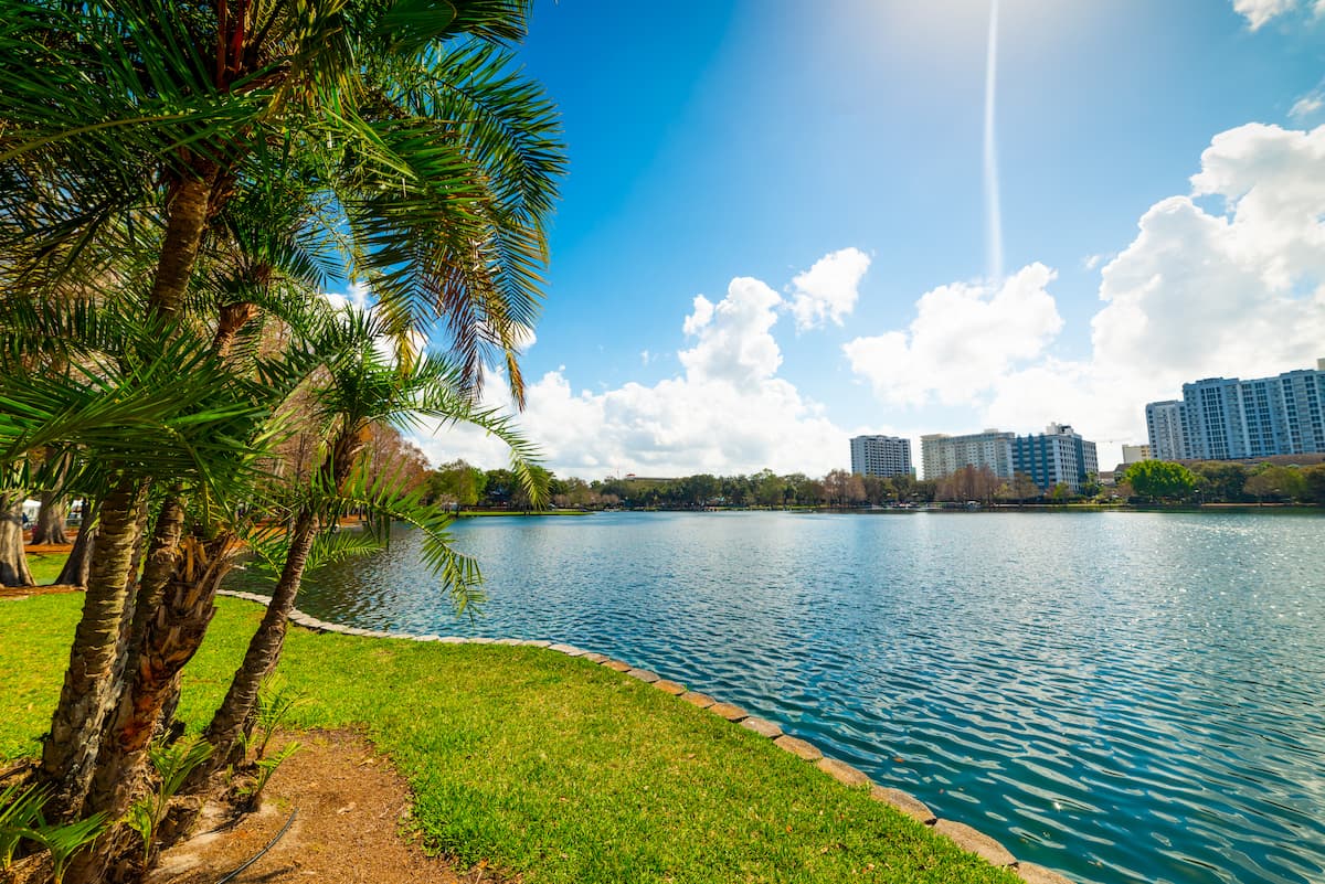 Looking across Lake Eola at park with trees in the foreground and skyline in the background on a sunny day