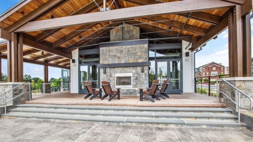 An open-air pavilion with seating around a fireplace.