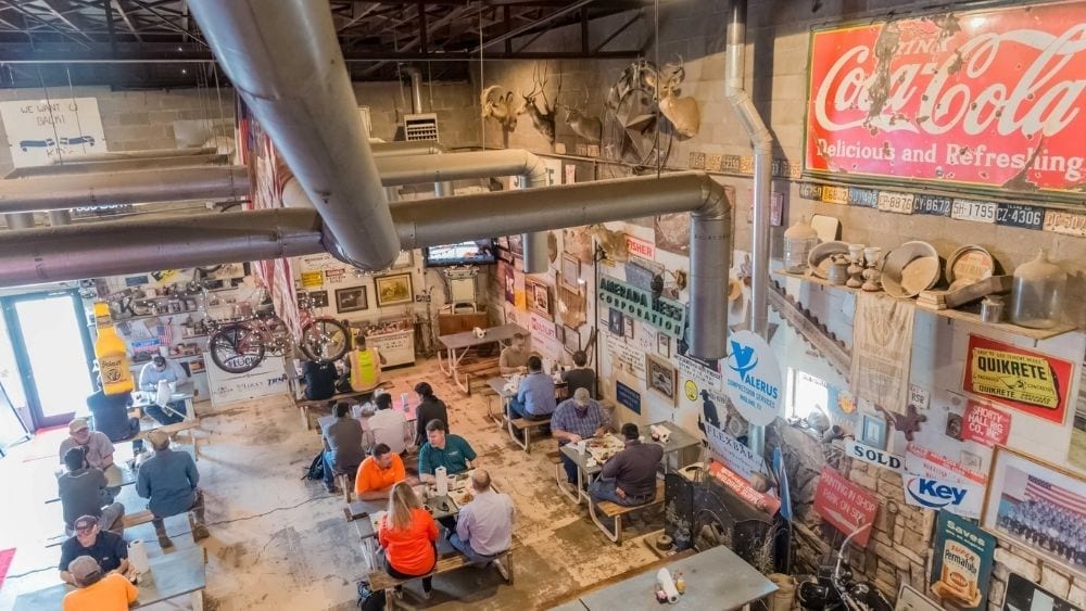 Interior view of a restaurant with people sitting at picnic tables.