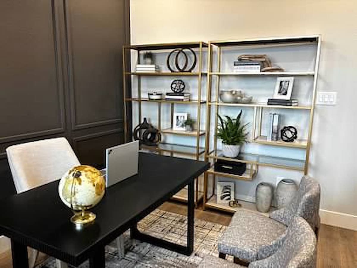 Home office with gold toned shelving and an accent wall