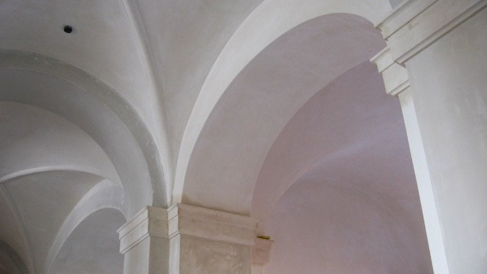 A white groin vault ceiling with pillars supporting it.
