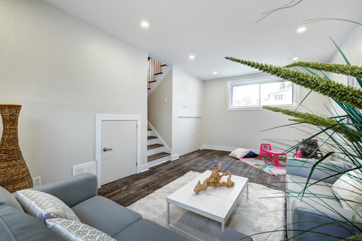 Family room in finished basement, with sofa, play area and white table with rug