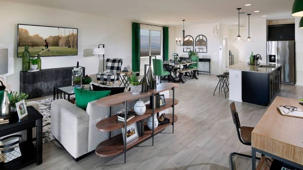 An open-concept living room that leads into a modern kitchen with green accents.