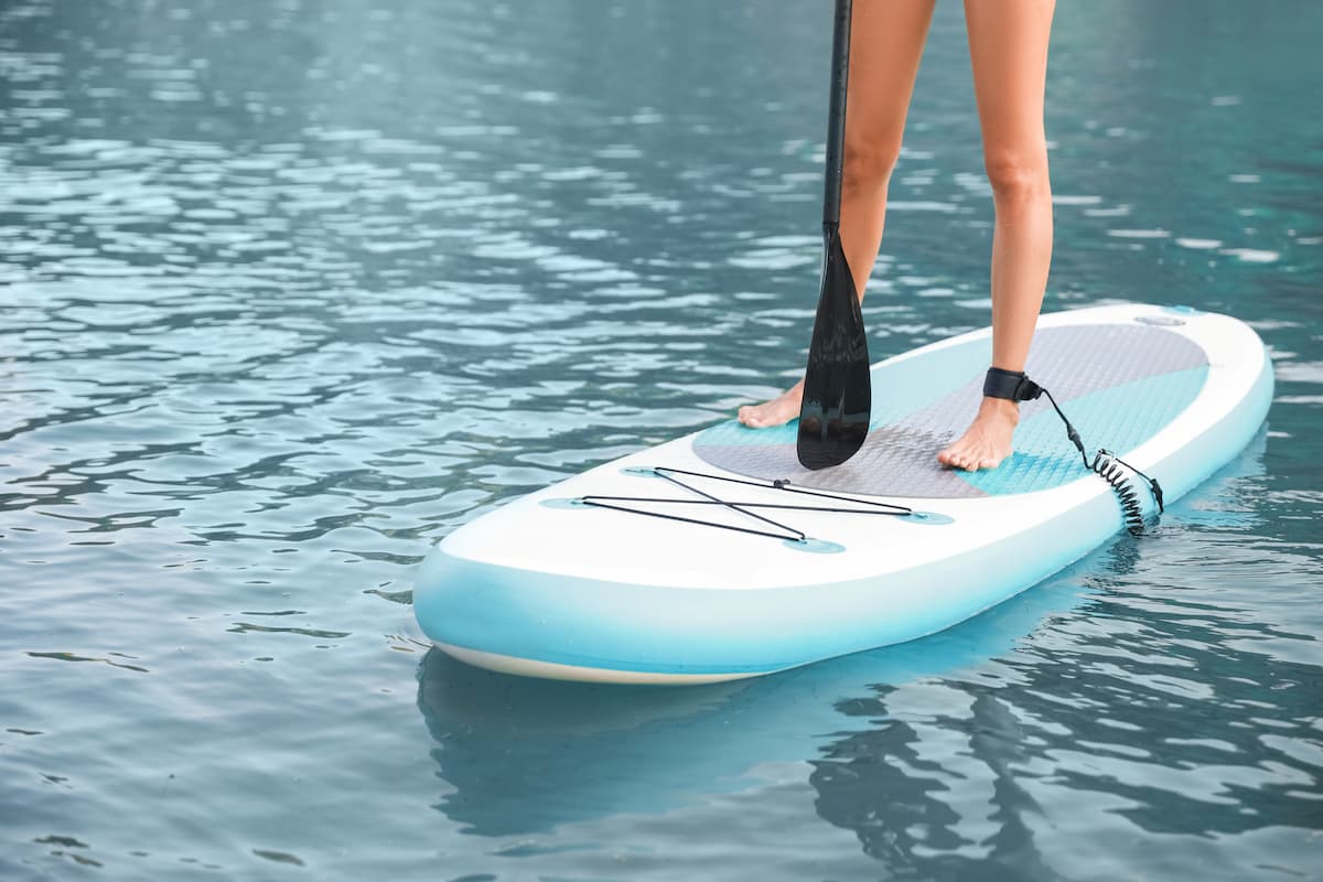 light blue paddleboard with someone standing with oar