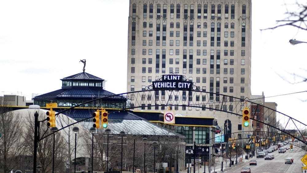 welcome sign over road that says “Flint Vehicle City”