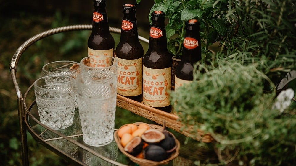 Metal bar cart with glasses, beer bottles and fruit.