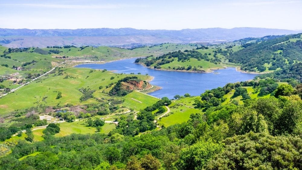 A wide river cuts through a green mountain valley.