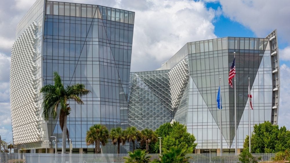 A modern, plain building with lots of buildings and flagpoles in front.