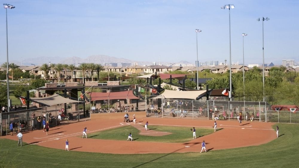 Aerial view of a little league softball game with a small crowd watching.