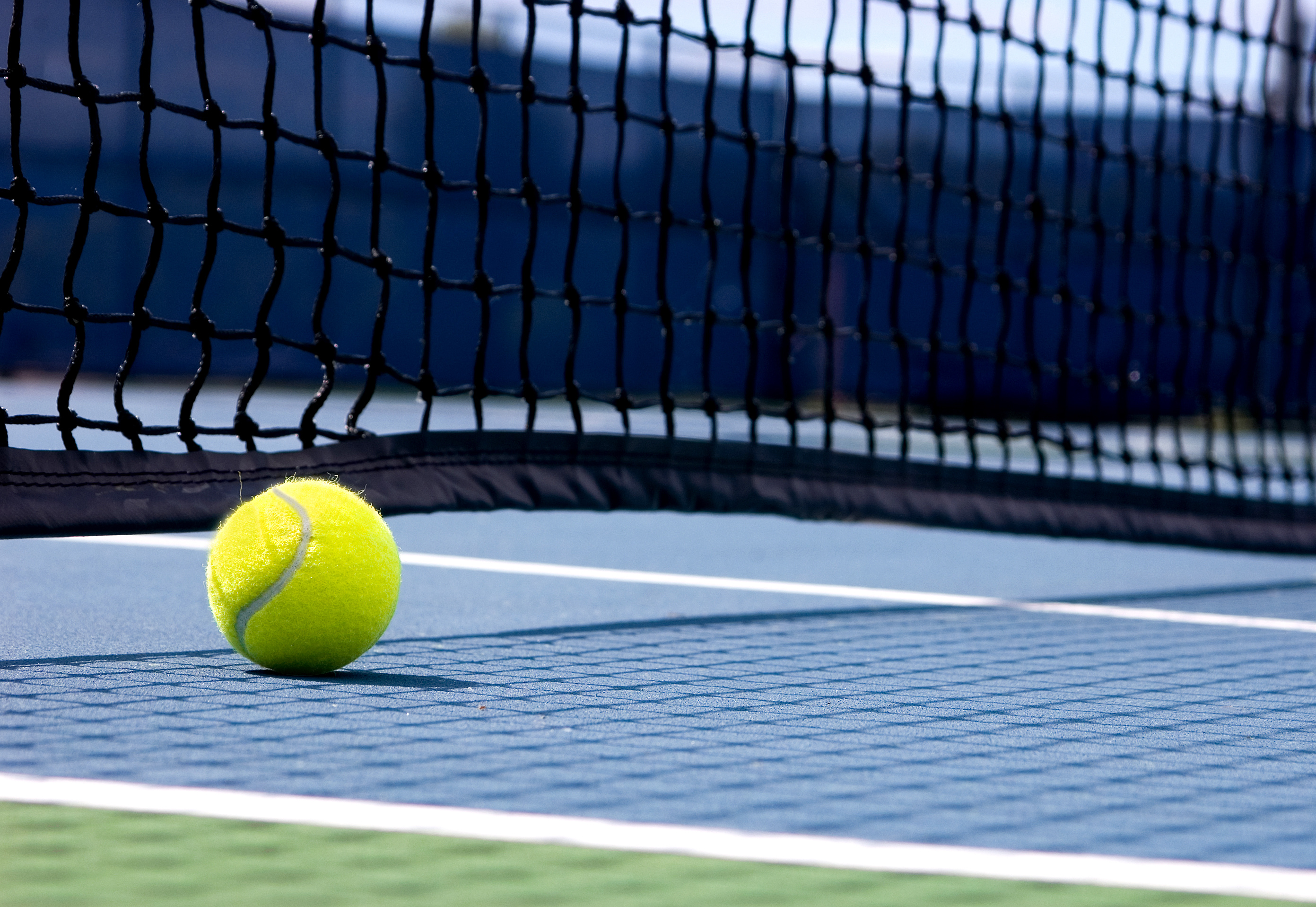 low vantage point of a ball on a tennis court next to net