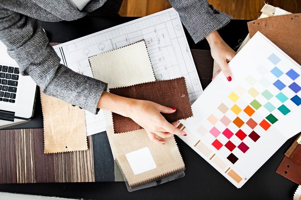 Woman sitting at desk looking at fabric samples and color swatches