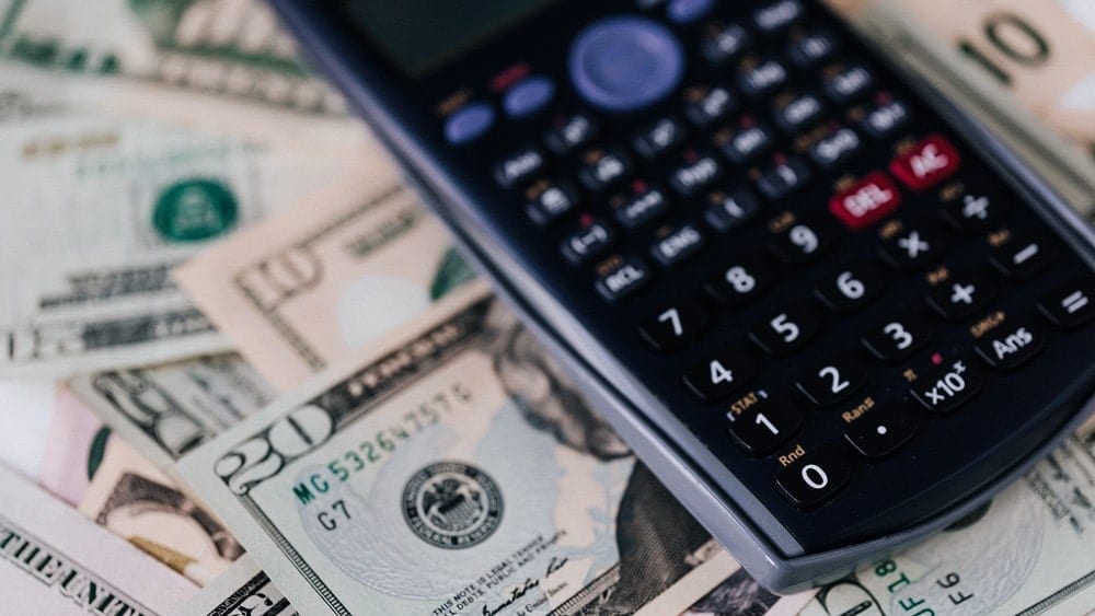 Calculator on top of a pile of paper money.