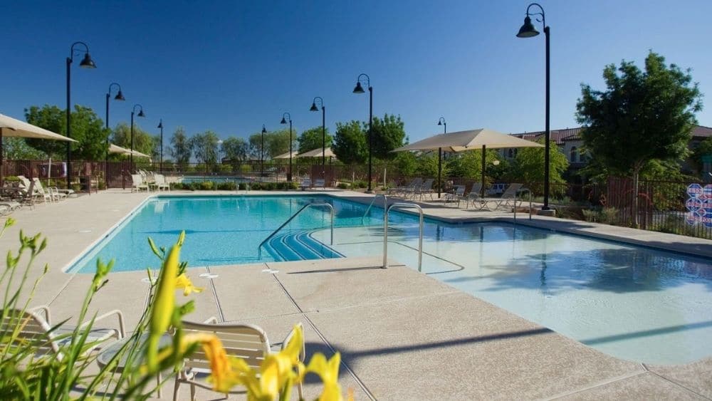 Community pool with plenty of seating and lamps.