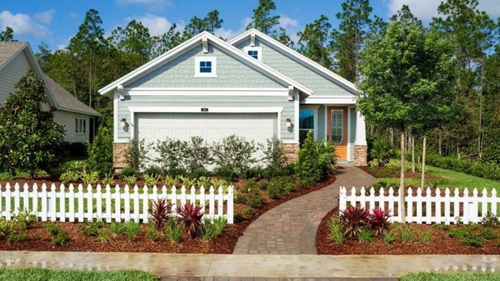 Single-story home with a manicured lawn and a white picket fence.