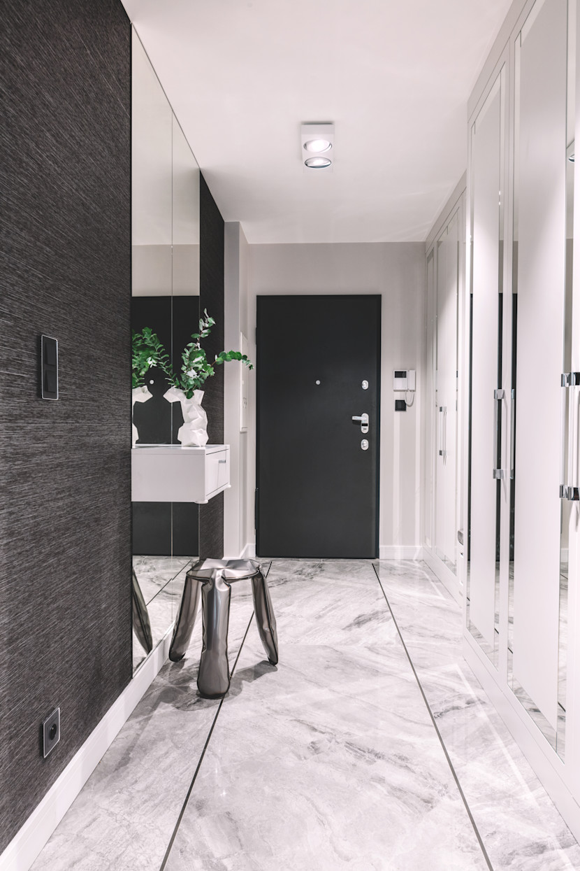 Front hallway with white marble floors and sliding black closet doors, with a bench and plant
