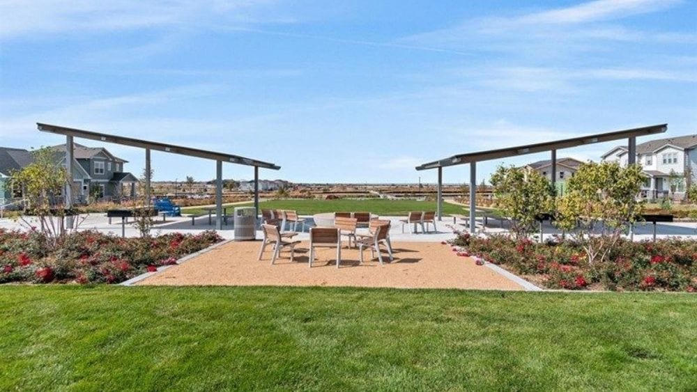 Two pavilions flanking a picnic area next to a grassy field.