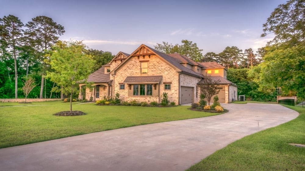 Traditional brick home on green lawn surrounding by trees