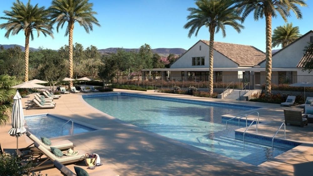 A community pool with seating and trees on a sunny day.