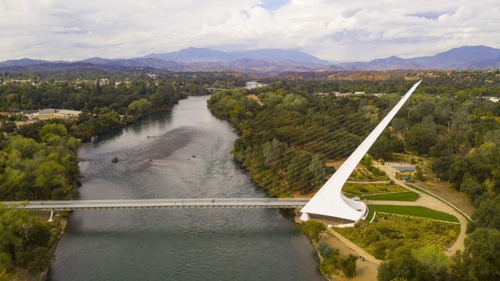 A modern tension bridge spanning a river and connecting the two banks.