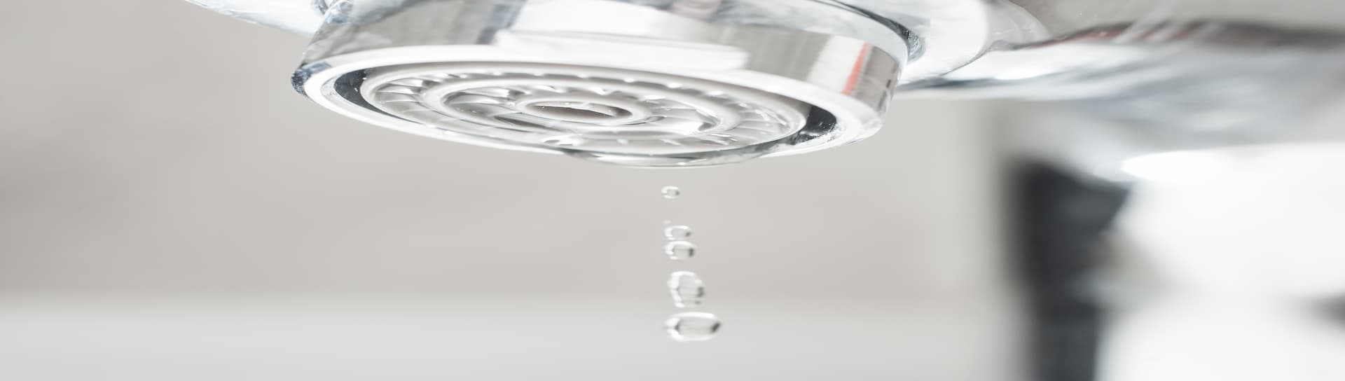 A chrome faucet with a small amount of water droplets