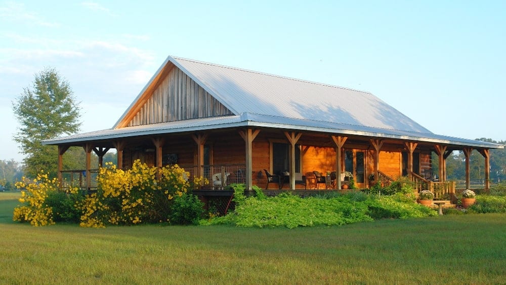 rural home, barn-style bungalow, with wrap-around porch and bushes