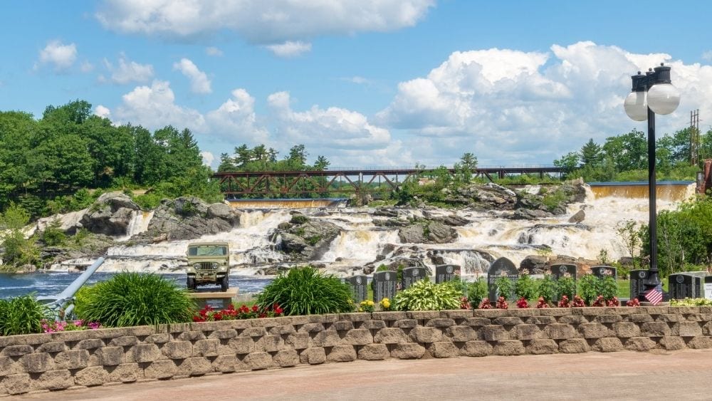 View from a bridge of a rocky waterfall formation in a park.