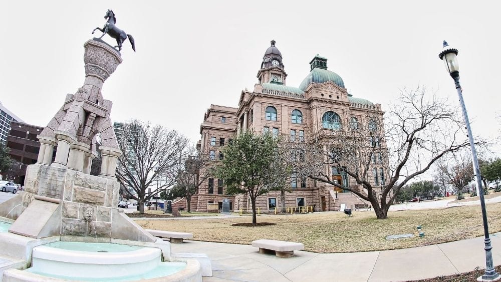 Panoramic view of a horse statue, courthouse, and iron lamppost.
