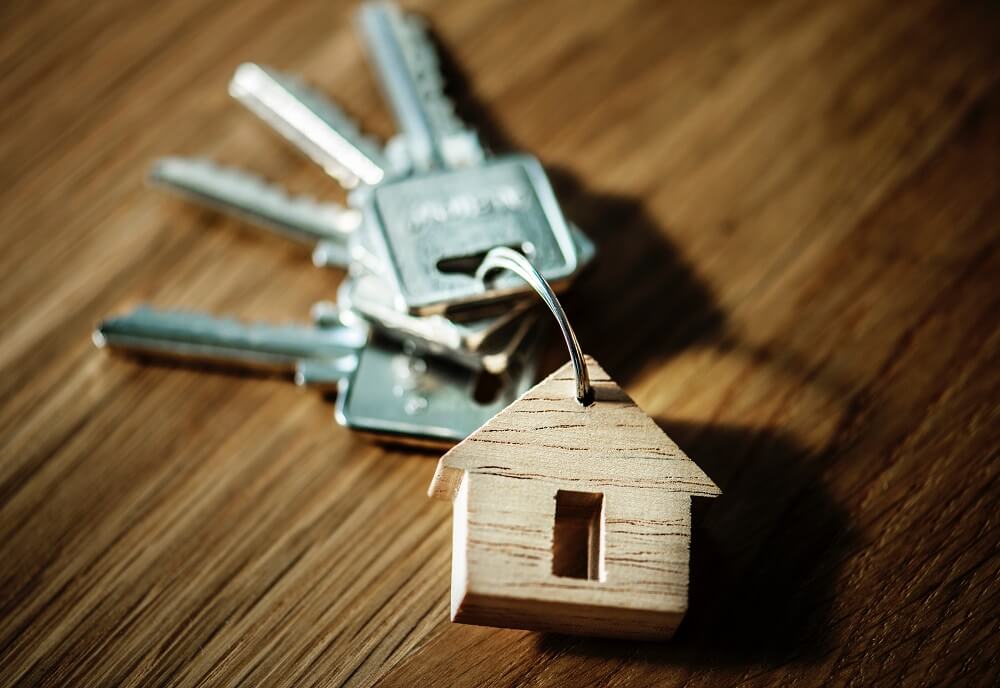 set-of-keys-with-house-keychain-on-wooden-desk