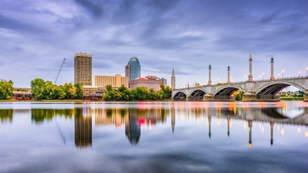 View from the water of a city skyline and bridge over the water.