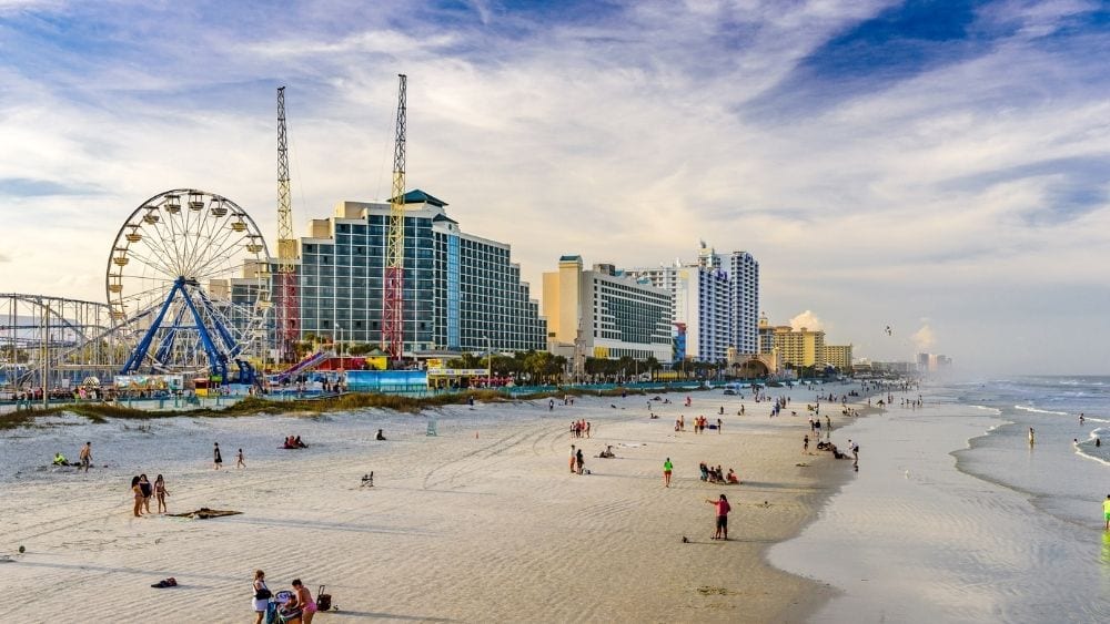 beach with Ferris wheel, large buildings and people on the sand