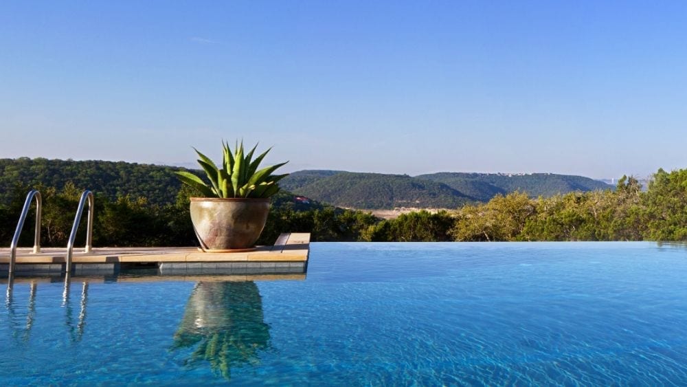 stunning infinity pool overlooking mountains with large potted cactus on pool deck