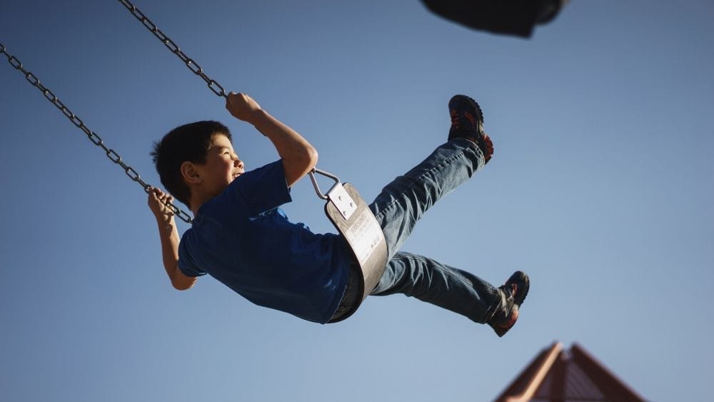 kid on a swing with legs up in the air